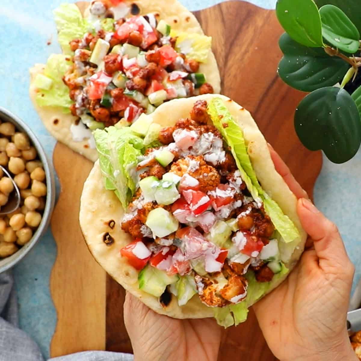two hands holding a chickpea and cauliflower wrap.