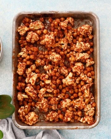 brown cauliflower and chickpeas in a metal sheet pan.
