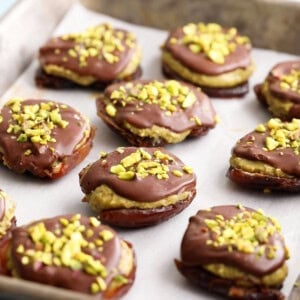 brown and green chocolate pistachio date bites on a metal baking sheet.