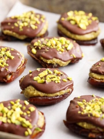 brown and green chocolate pistachio date bites on a metal baking sheet.