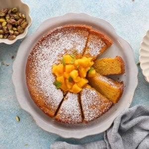 one round yellow mango cake in a white platter.