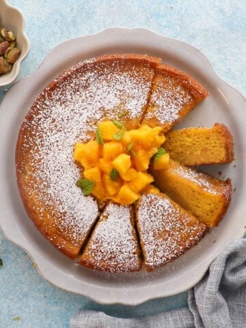 one round yellow mango cake in a white platter.