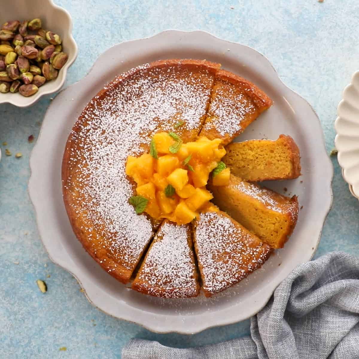 one round yellow mango cake in a white platter.