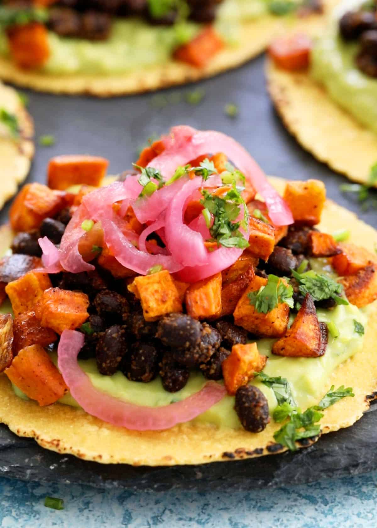 1 sweet potato and black bean tacos on a black platter.