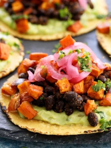 sweet potato and black bean tacos on a black platter.