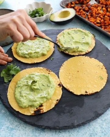 4 sweet potato and black bean tacos on a black platter.