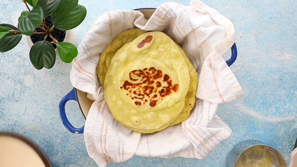 green colored naan stacked in a white cloth.