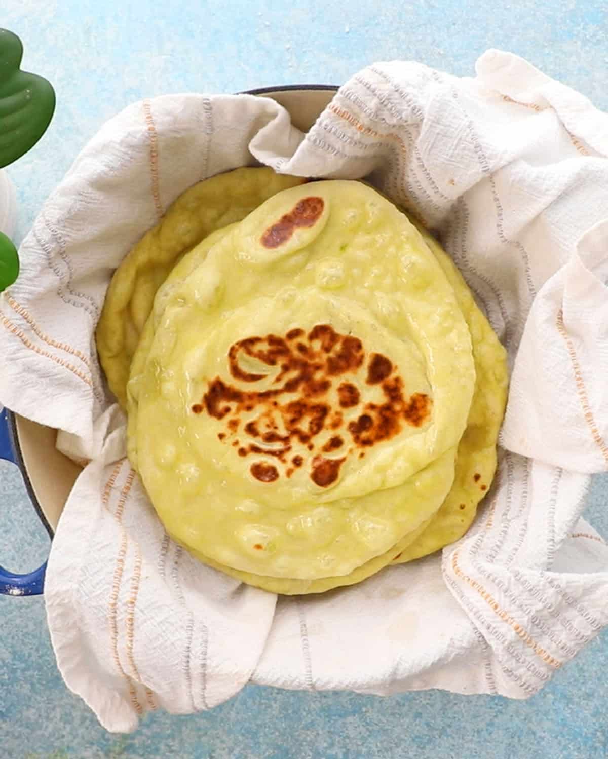 green colored naan stacked in a white cloth.