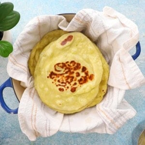 green colored naan stacked in a white cloth.