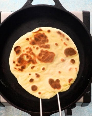 one yellow naan bread in a black skillet.