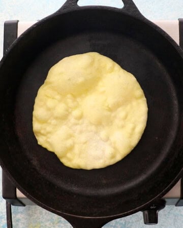 one yellow naan bread in a black skillet.