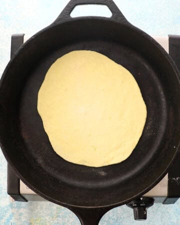 one yellow naan bread in a black skillet.