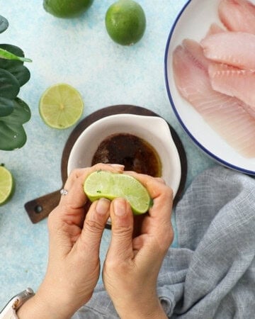 two hands squeezing a green lime.