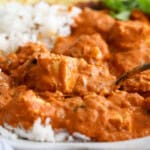 orange tofu tikka masala and white rice in a white bowl.