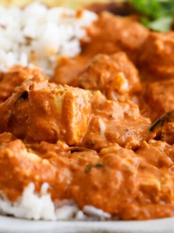 orange tofu tikka masala and white rice in a white bowl.