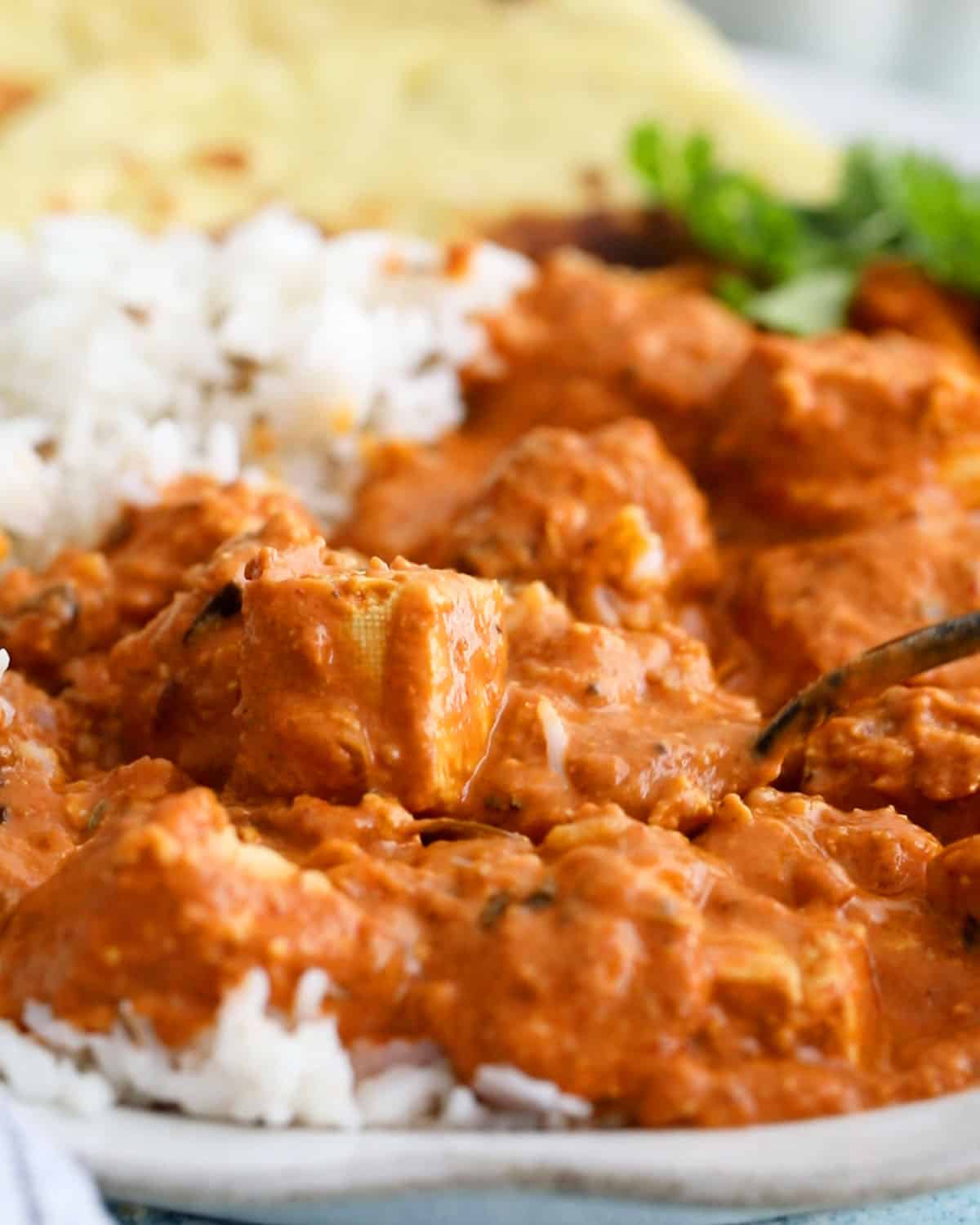 orange tofu tikka masala and white rice in a white bowl.