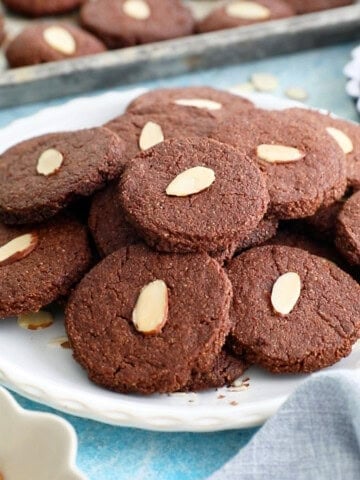 brown almond chocolate cookies on a white plate.