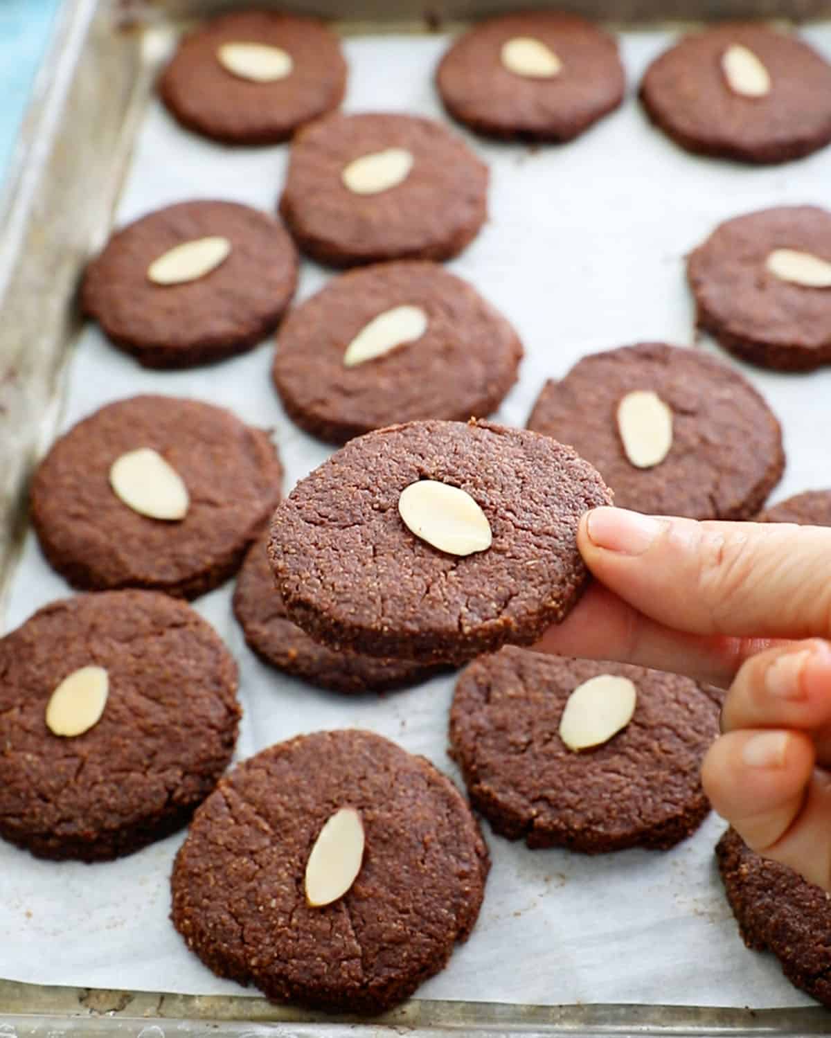 a hand holding one brown almond flour chocolate cookie.