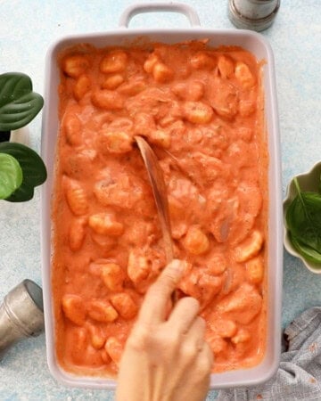 orange and white gnocchi and chicken in a grey baking dish.
