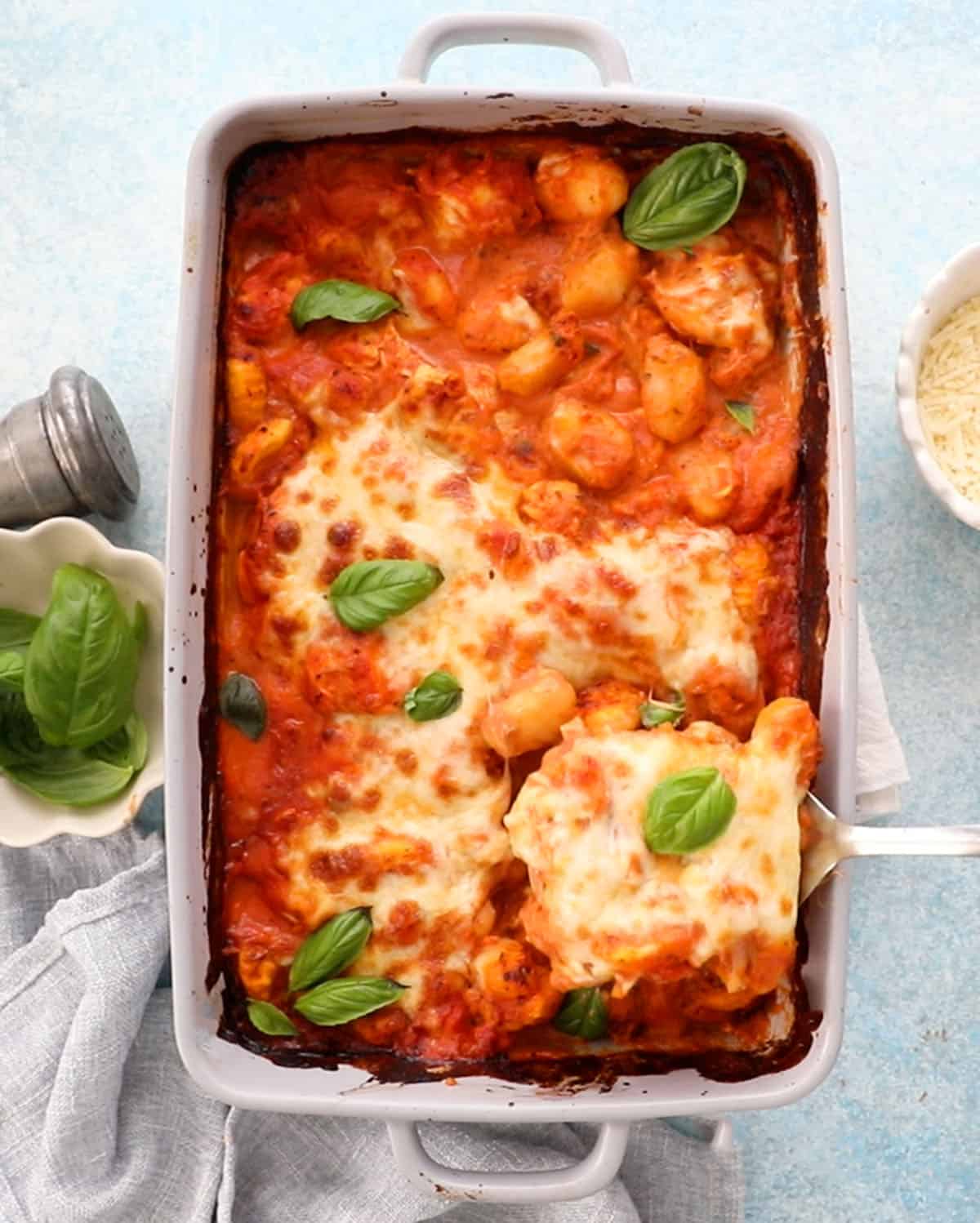 orange and white gnocchi chicken in a grey baking dish.