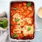 orange and white gnocchi chicken in a grey baking dish.