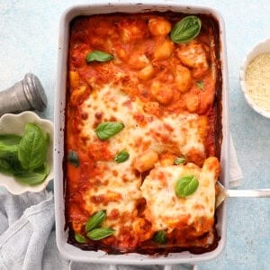 orange and white gnocchi chicken in a grey baking dish.