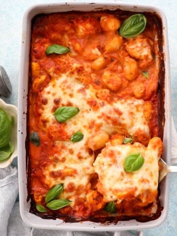 orange and white gnocchi chicken in a grey baking dish.